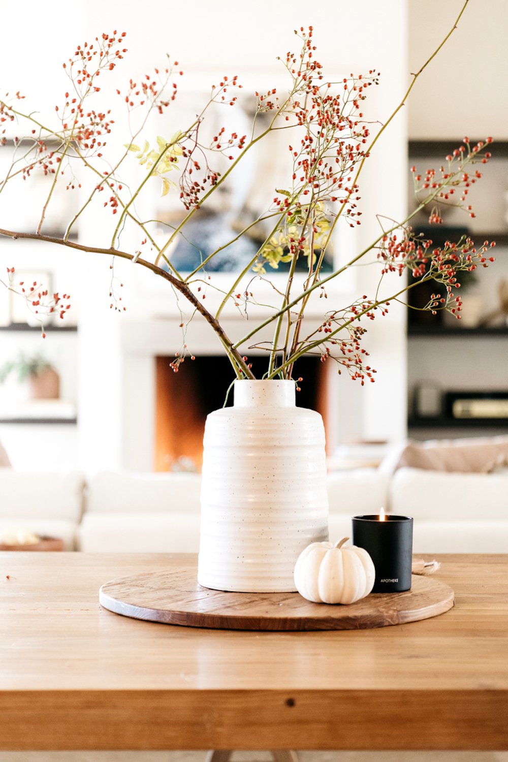 Dried flower arrangement in white vase on wooden table.