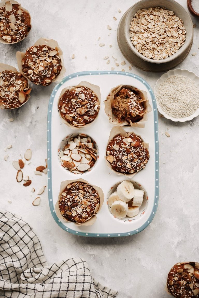 Overhead image of white tray of vegan banana muffins on marble countertop.