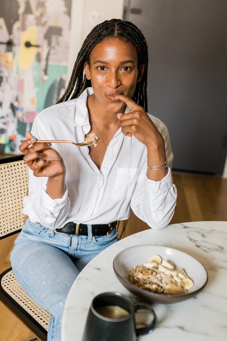 Woman eating oatmeal at breakfast table.