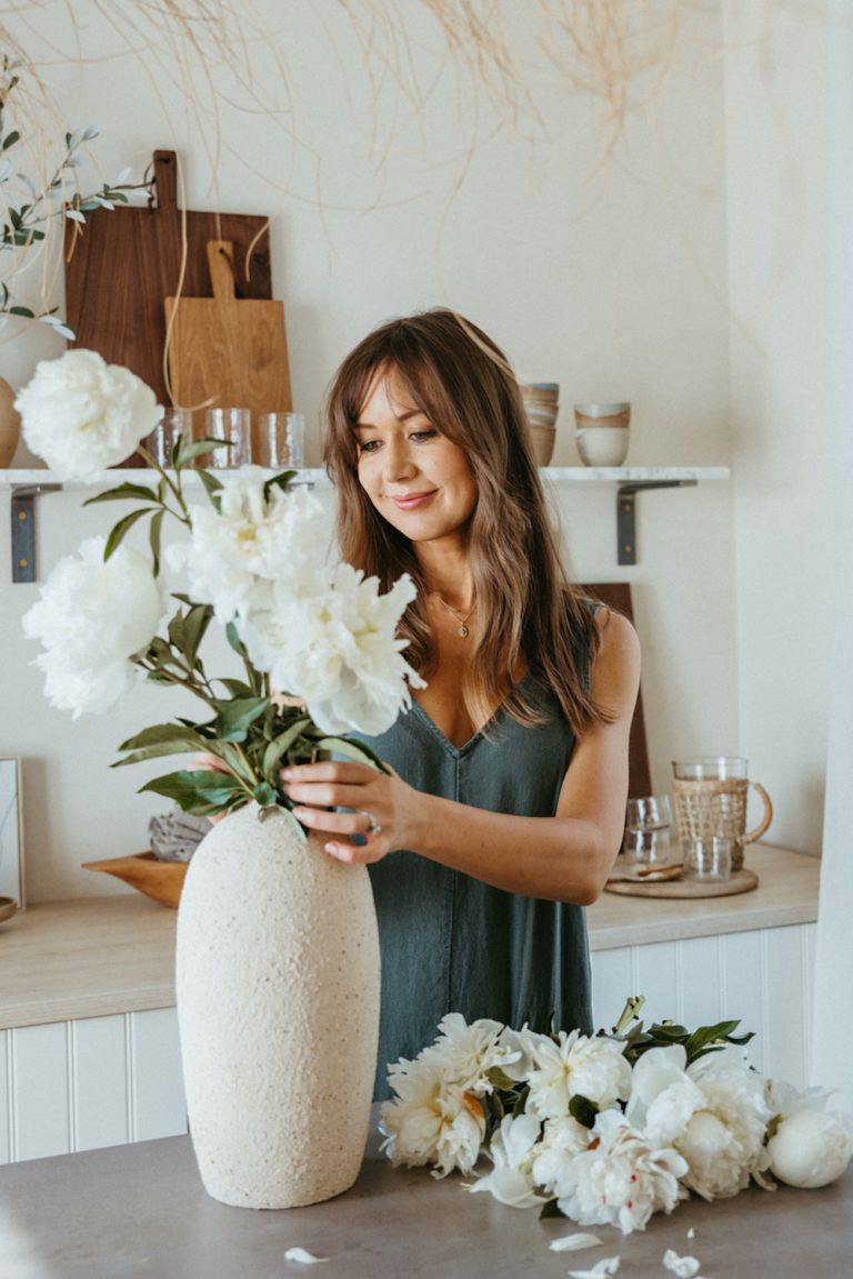 Camille Styles arranging white peonies in vase