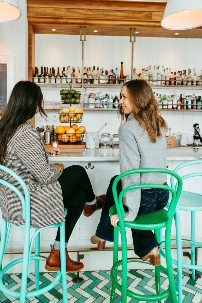 Two women talking at bar.