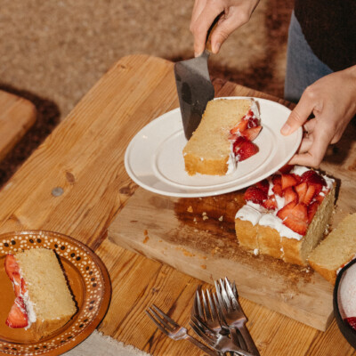 Serving slices of gluten-free citrus cake with strawberries.