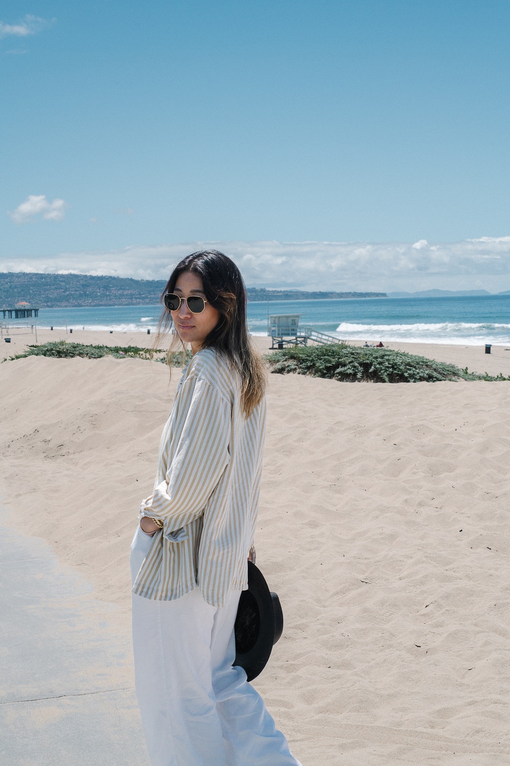 Jennie Yoon wearing white linen shirt and pants on the beach.