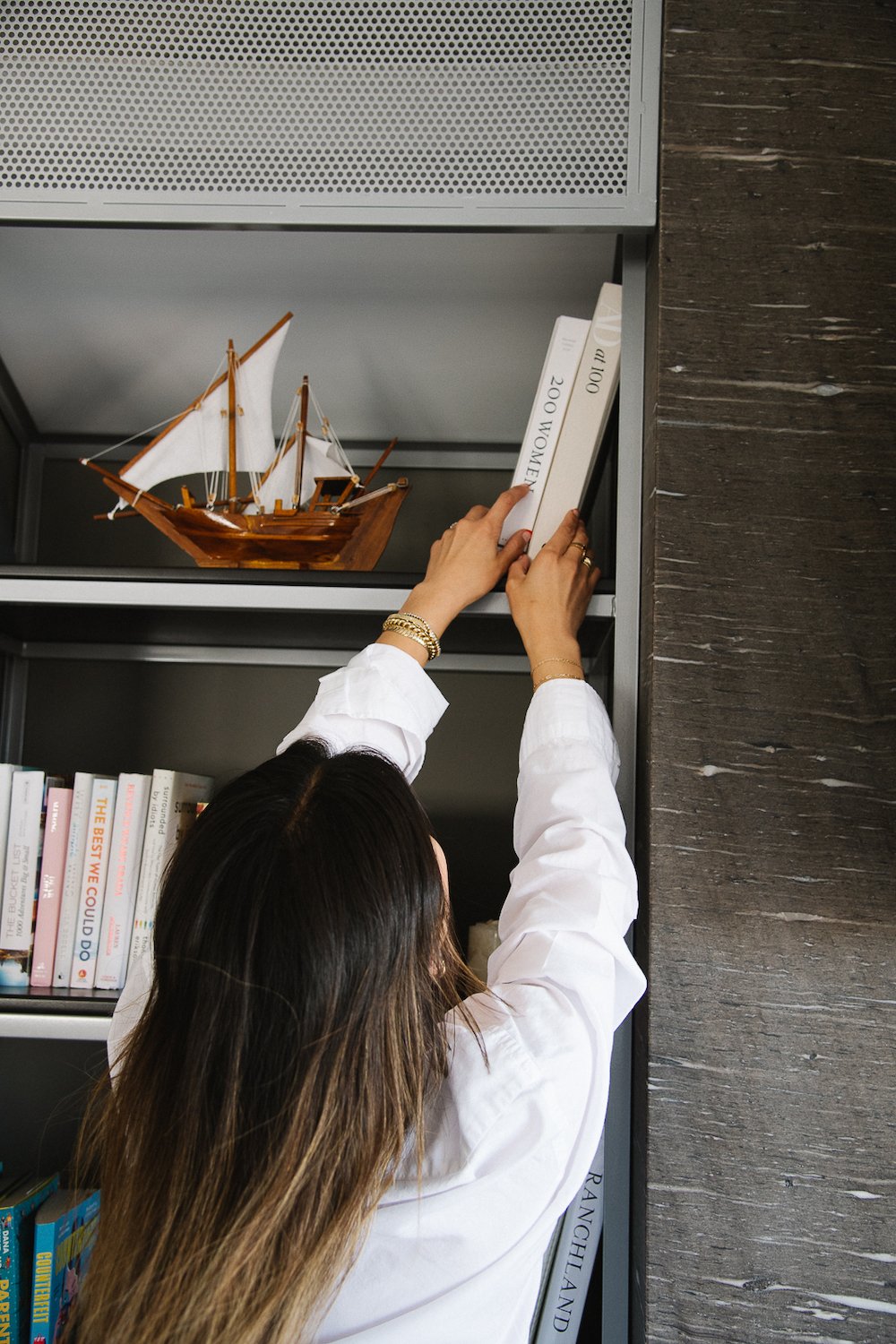 Jennie Yoon stacking books on a bookshelf.