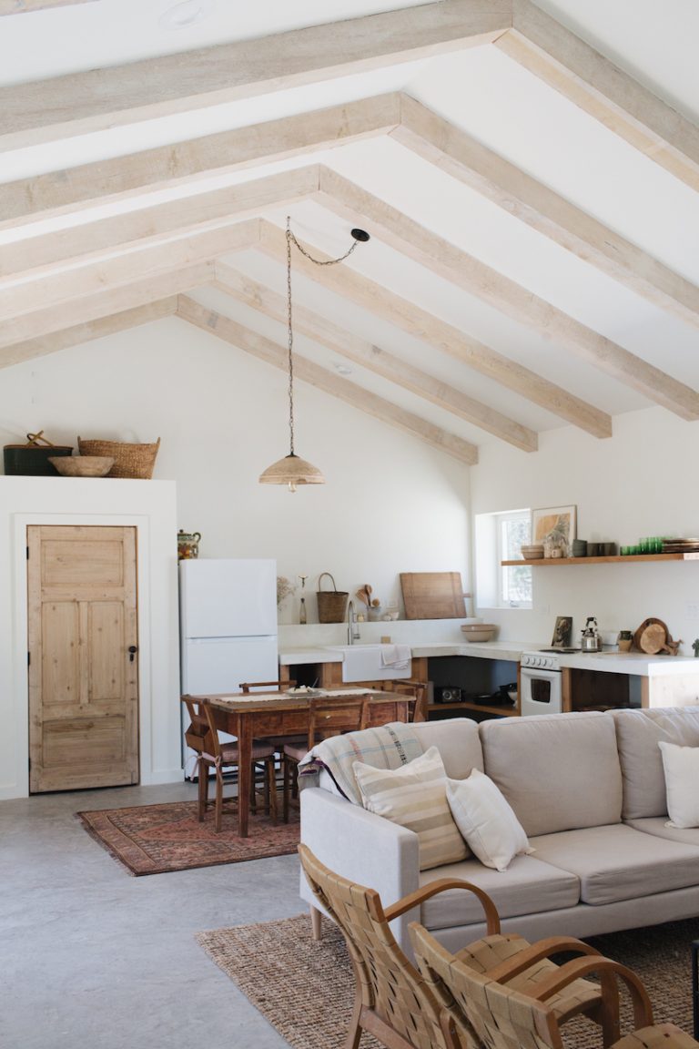 آشپزخانه زیبای کلبه‌ای سبک و مطبوع با دیوارهای سفید و پرتوهای چوبی سبک.