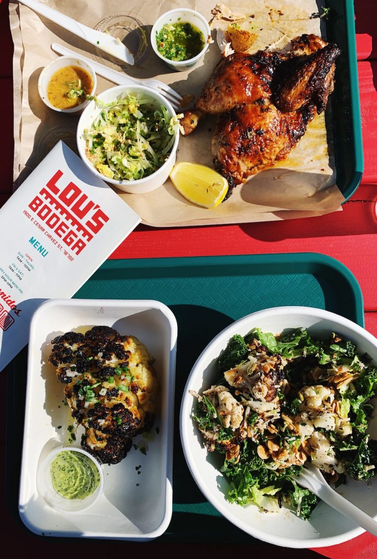 Salad, roasted cauliflower, and chicken on trays at Lou's Bodega in Austin, Texas.