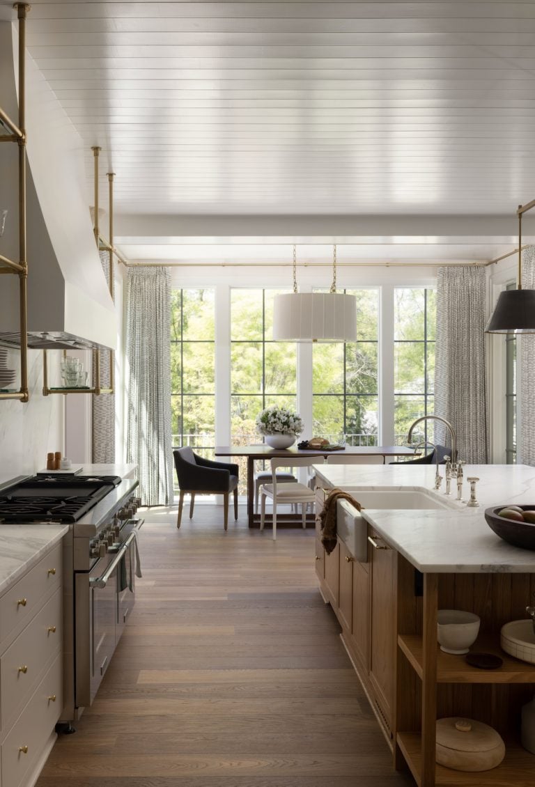 Tendência de luxo tranquila em cozinha moderna e leve com bancada de mármore, fogão de seis bocas e armários de madeira.