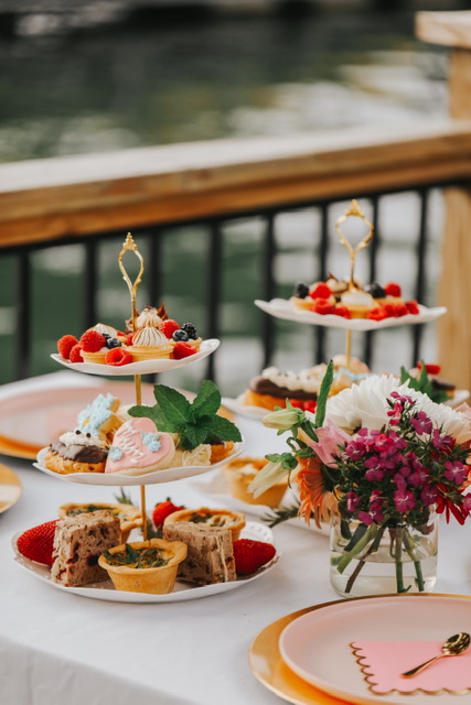 Three-tiered platters of pastries and bouquet of flowers on picnic table at Mozart's Coffee Roasters in Austin, Texas.