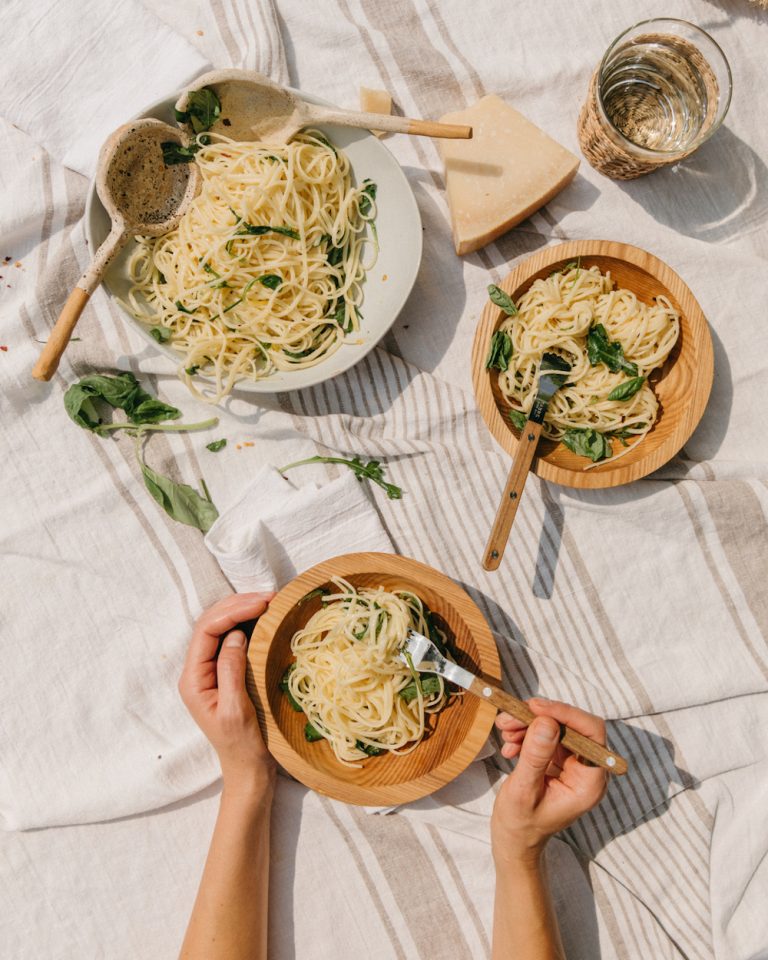 Bowls of pasta on picnic blanket.