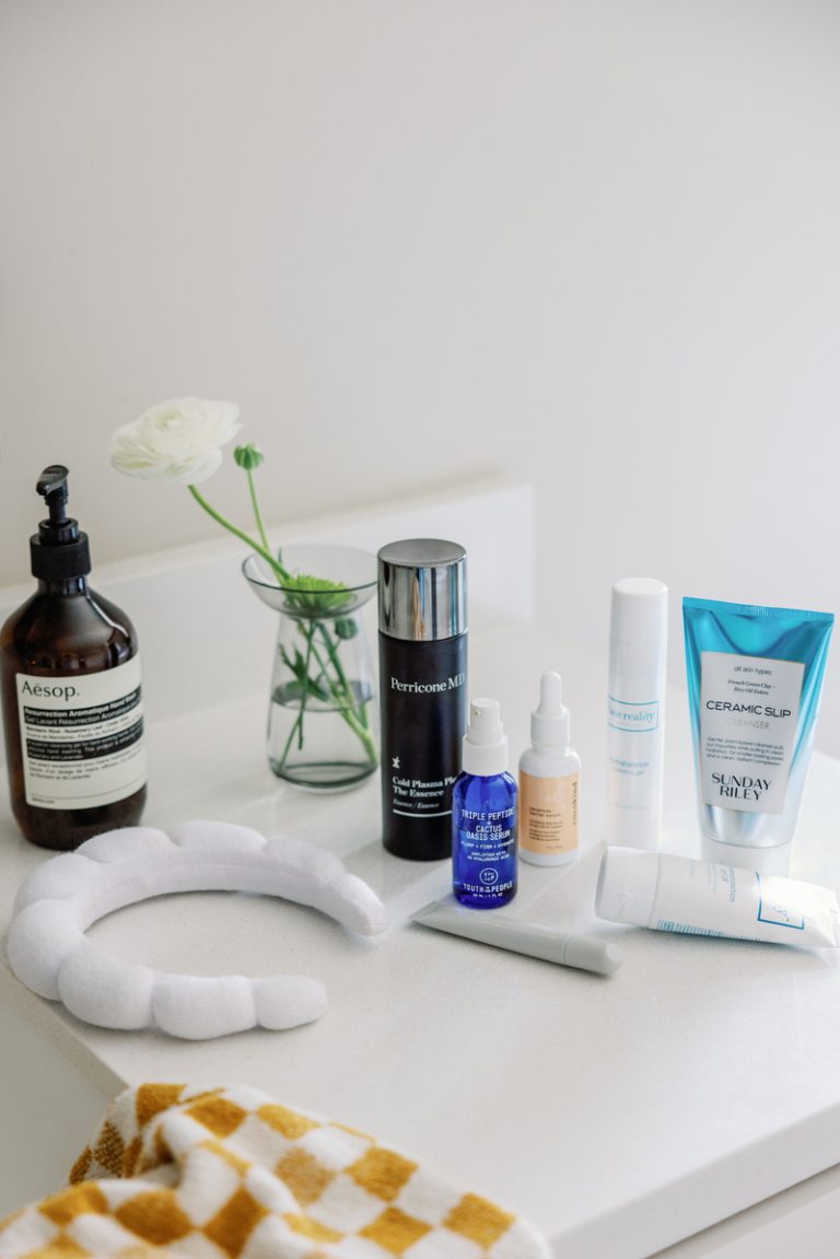 Productos para el cuidado de la piel en un mostrador de baño blanco.