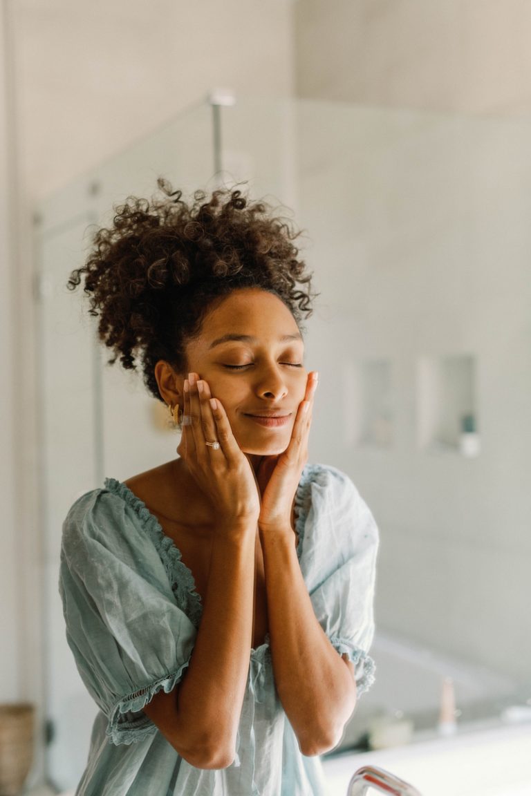 Woman washing face in mirror.