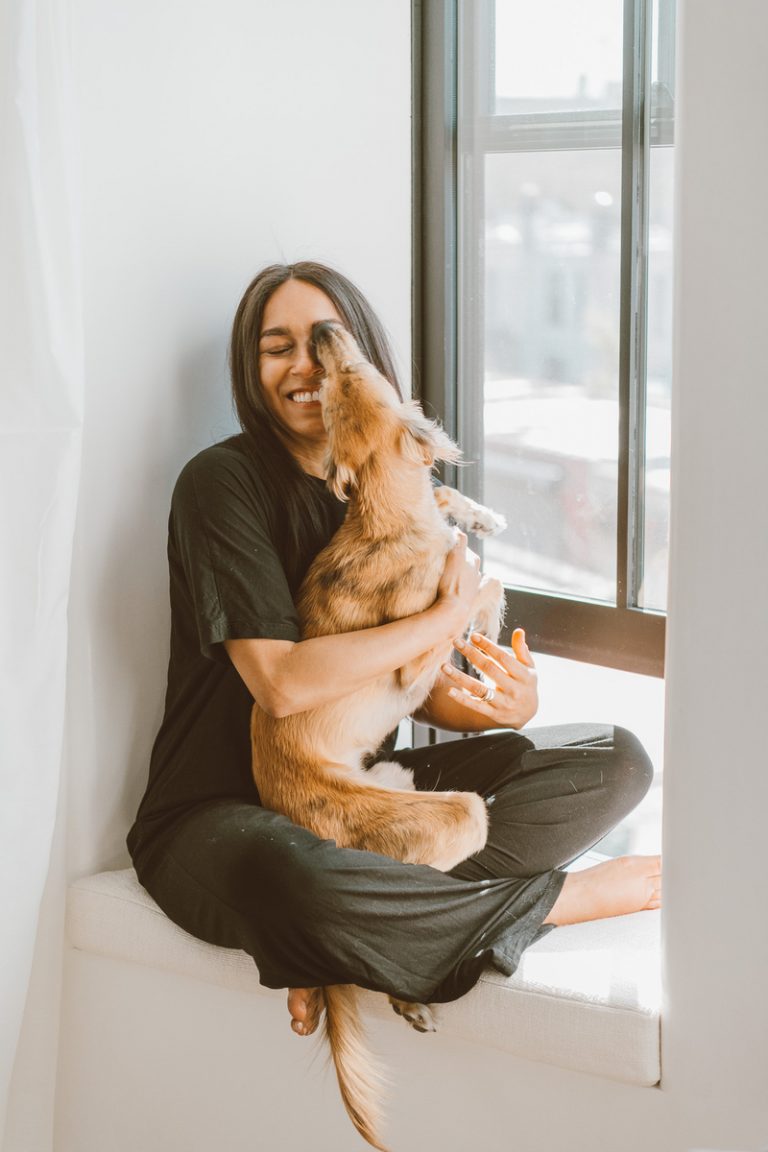 Brunette woman sitting in windowsill holding dog.