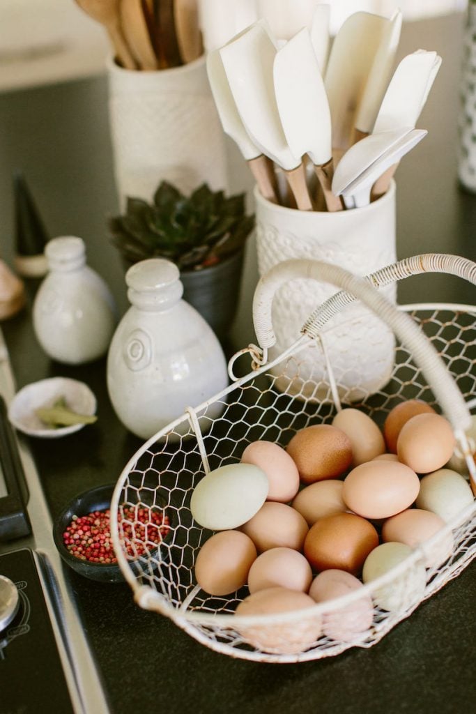 Basket of farm eggs in different colors on kitchen counter.