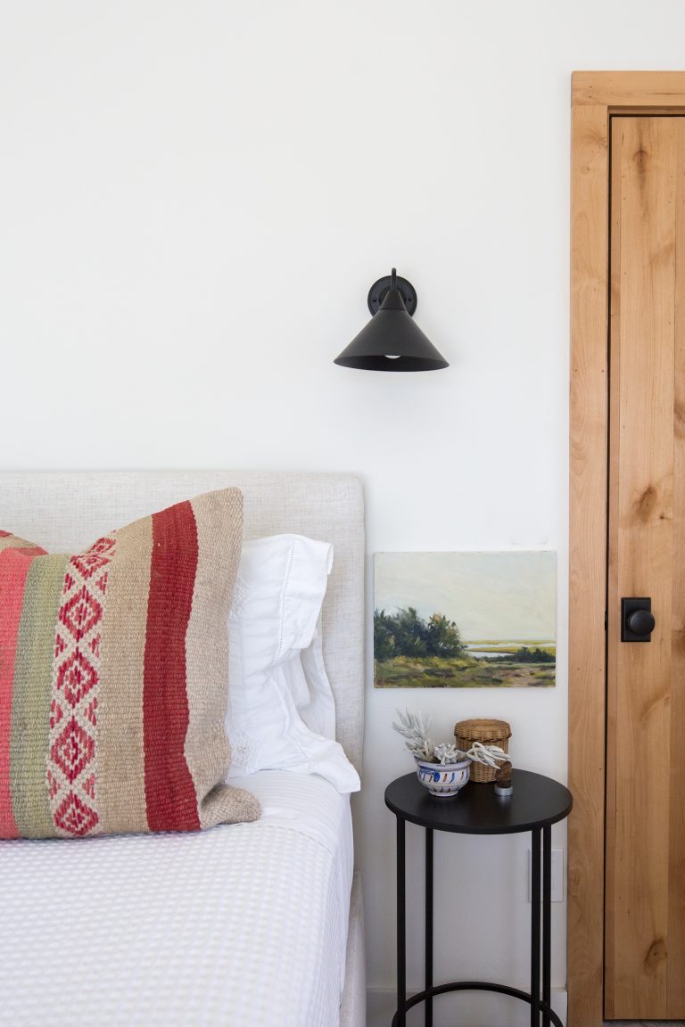 White bedroom, white sheets, black candlesticks, black nightstands and Aztec patterned pillows.