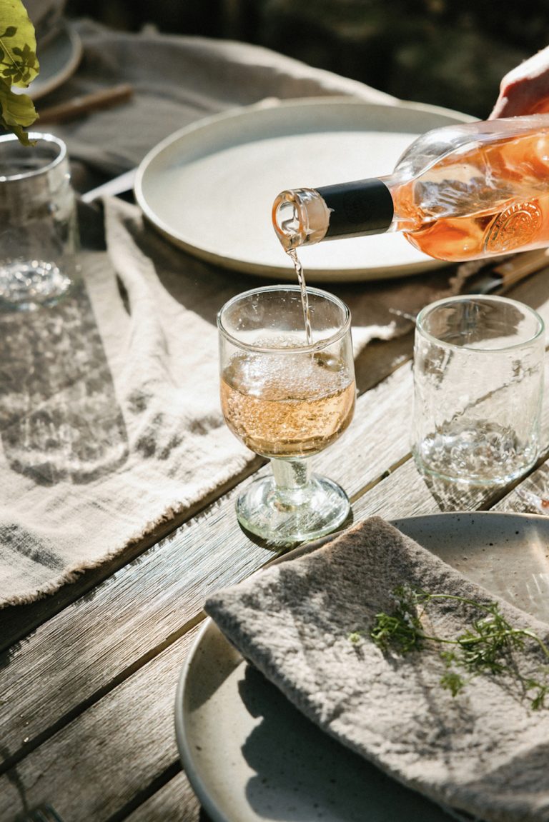 Wein in Gläser auf dem Tisch im Freien gießen.