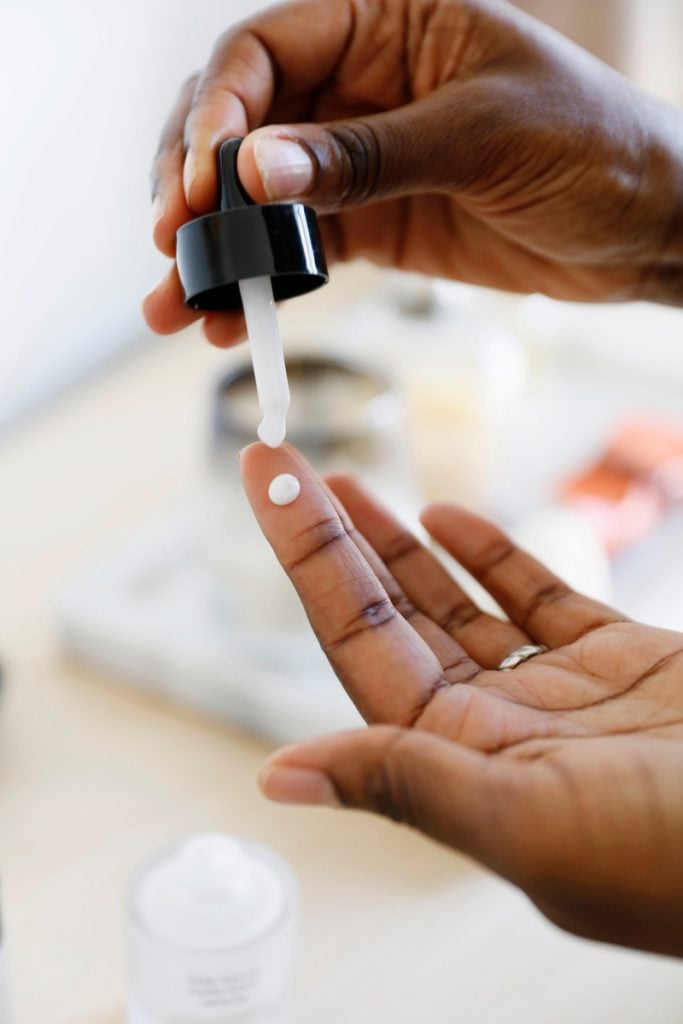 Hand dropping skin serum onto finger.