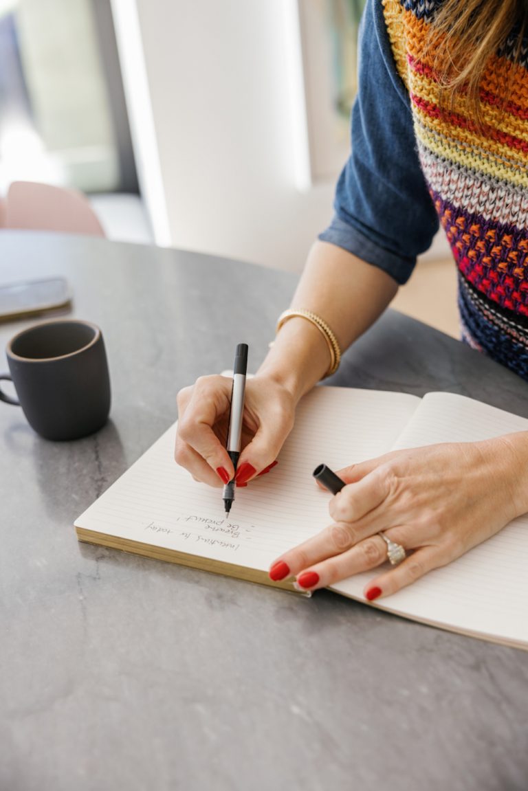 Woman with red manicure writing in journal.