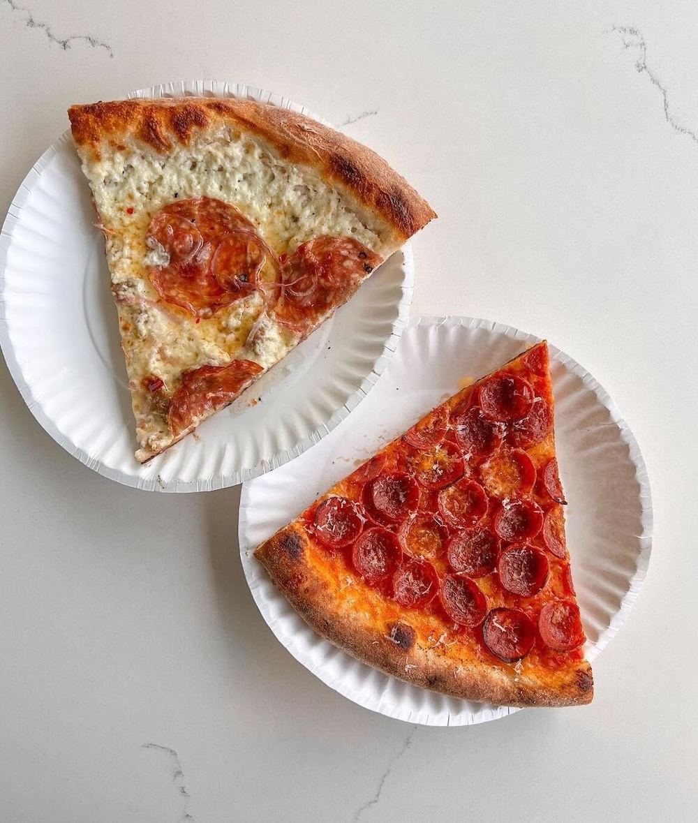 Two slices of pizza on white paper plates at All Day pizza in Austin, Texas.