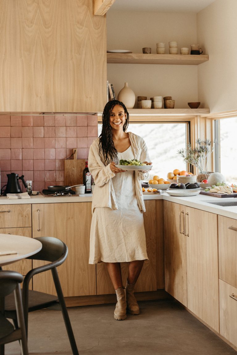 Brunette woman in linen dress cooking in the kitchen.