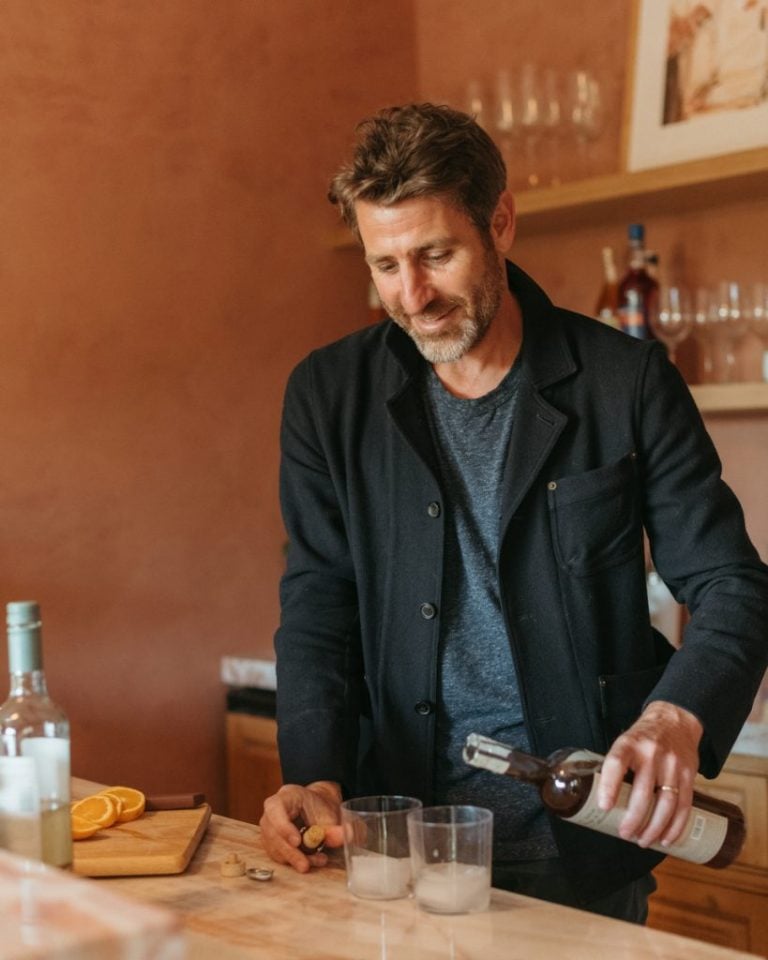 Brunette man pouring drinks at home bar.