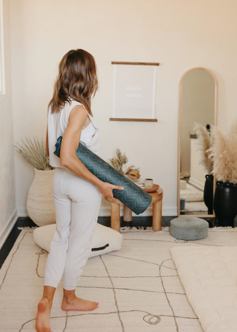 Brunette woman carrying a yoga mat.