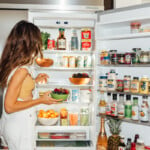 Brunette woman standing in front of open fridge.