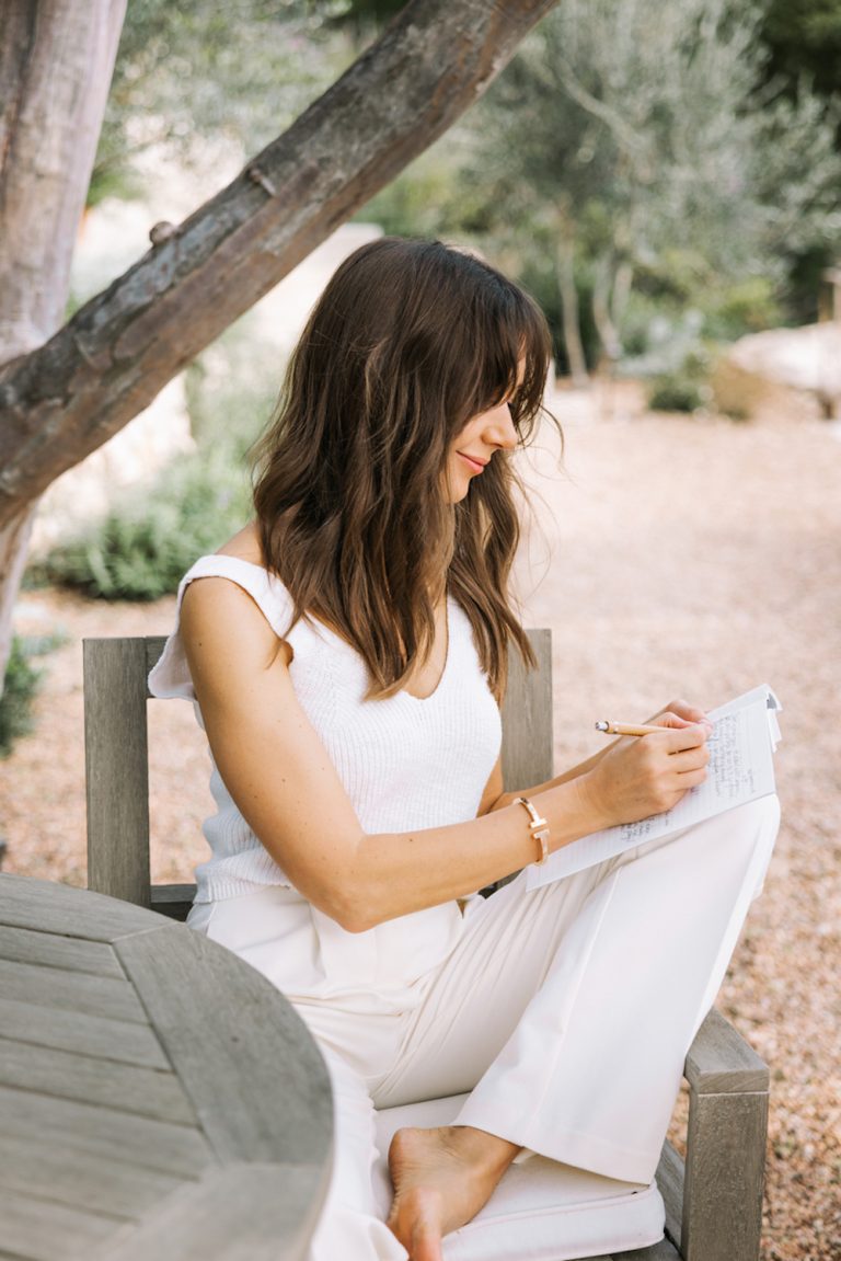 Brunette woman journaling outside.