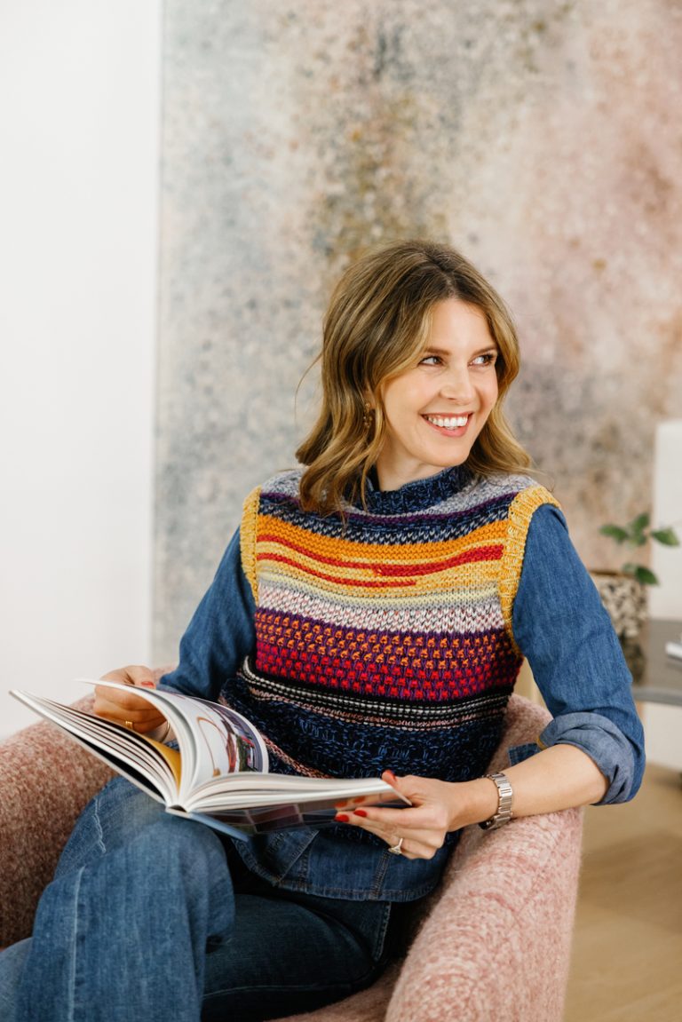 Brunette woman smiling while reading in chair.