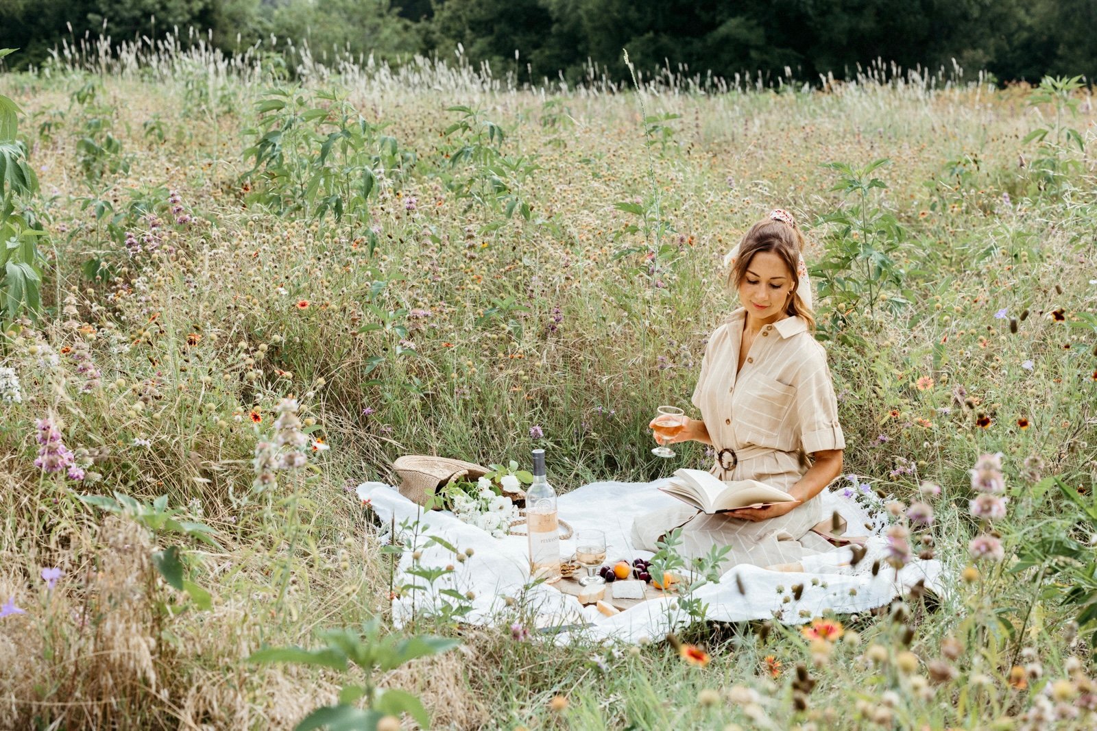 french inspired aesthetic picnic with a woman sitting in a field of wildflowers