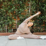 Megan Roup wearing pink sweatsuit stretching outside_how to improve gut health