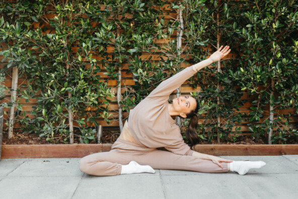 Megan Roup wearing pink sweatsuit stretching outside_how to improve gut health