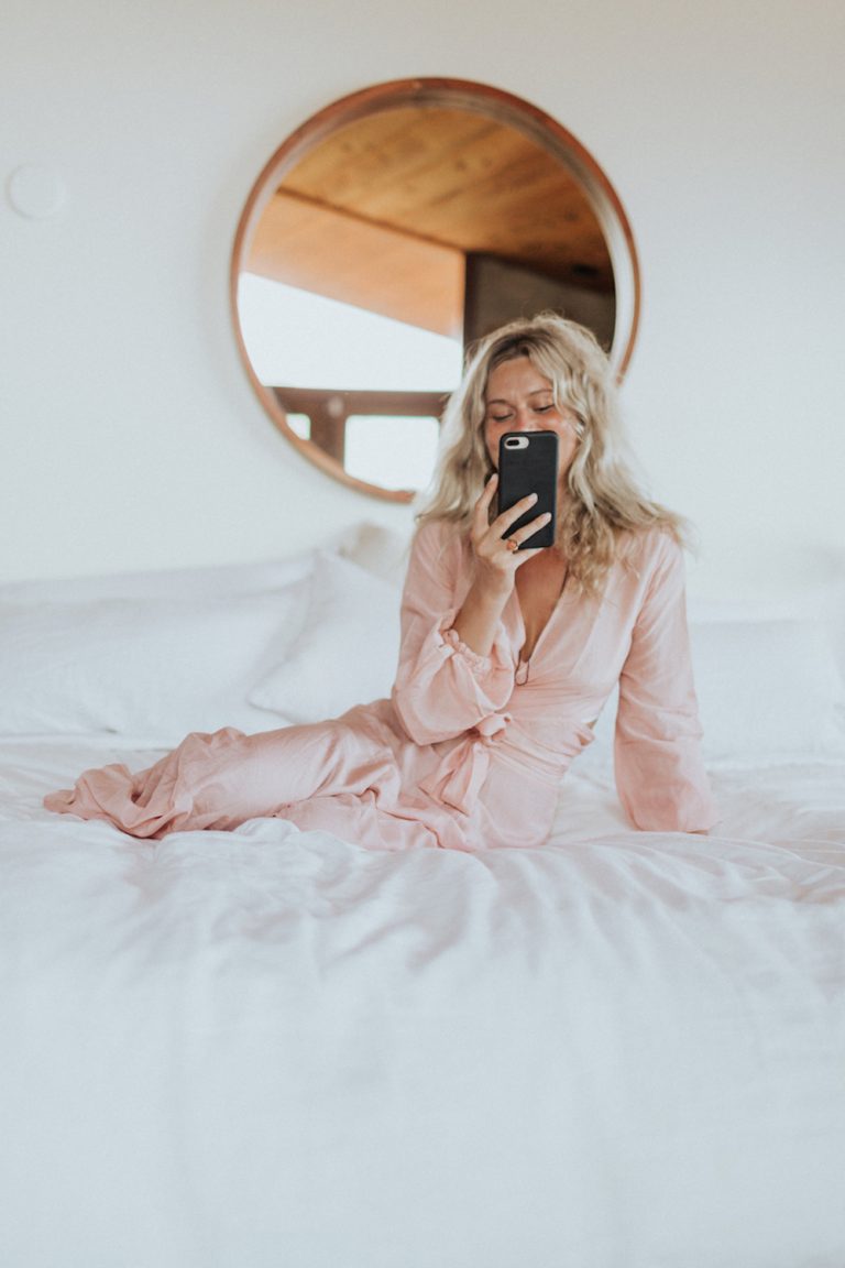 Blonde woman wearing pink nightgown looking at phone.