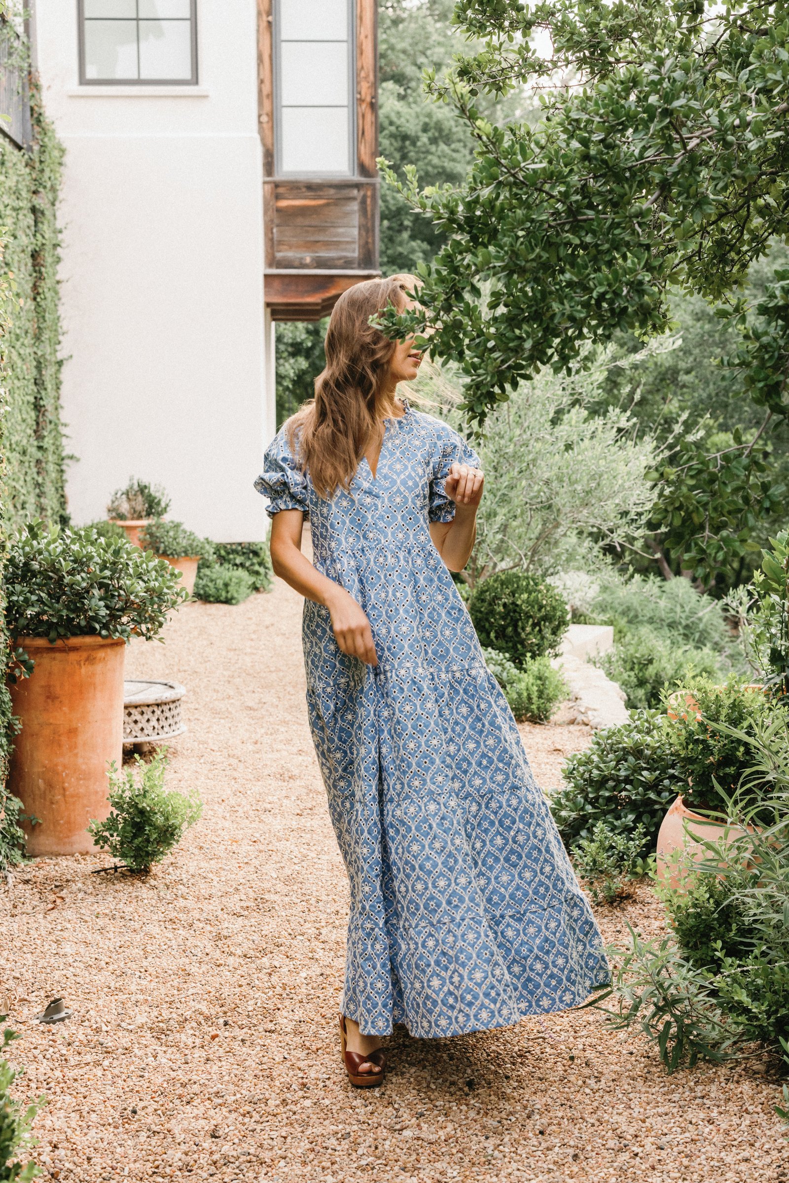camille in a blue maxi sezane dress in the backyard