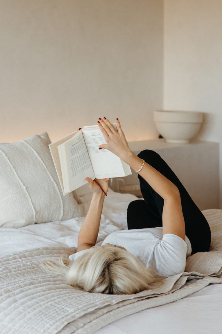 Blonde woman reading on bed.