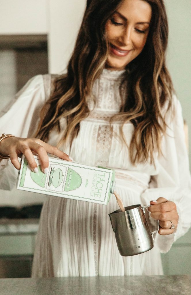 Brunette woman pouring Tache pistachio milk in canister.