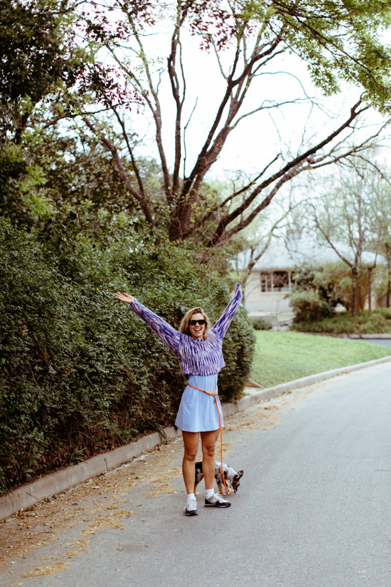 Blonde woman walking dog outside.