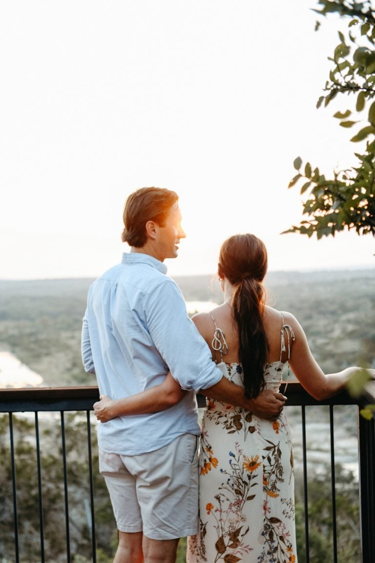 Couple embracing looking out at mountains on deck.