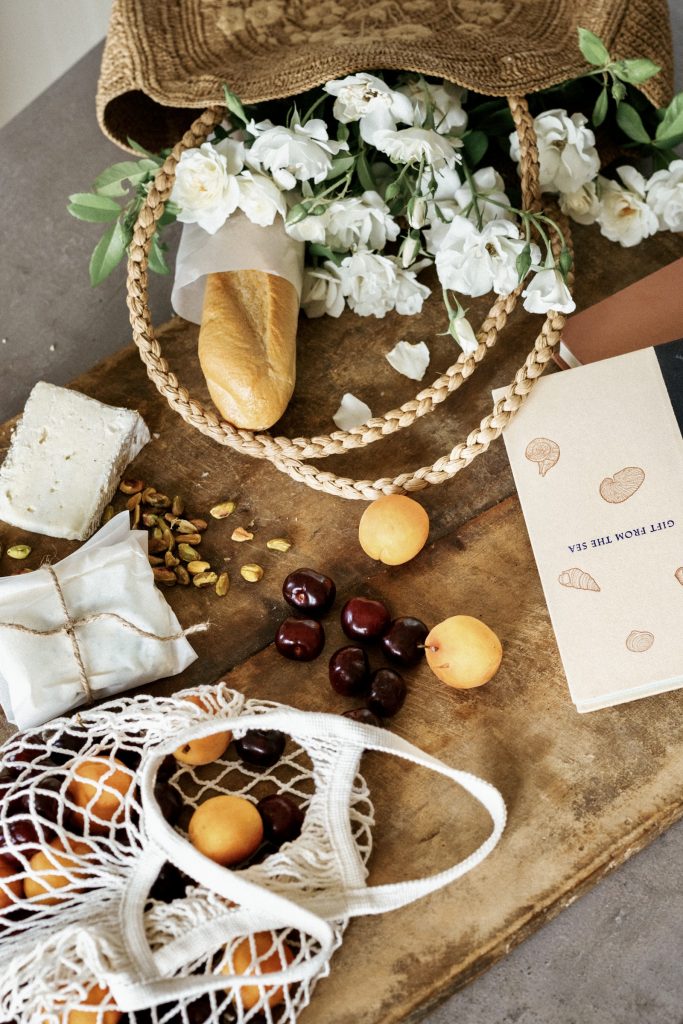 what to pack for an aesthetic picnic: board with baguette, stone fruit, cheese and book