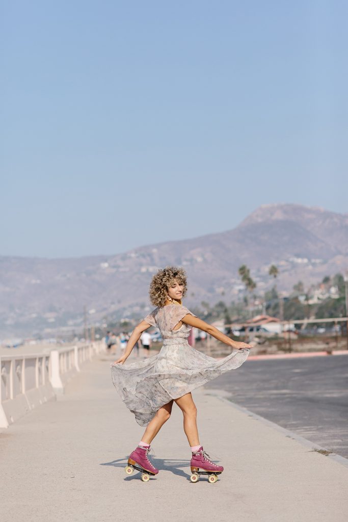 Woman wearing dress rollerblading in desert.