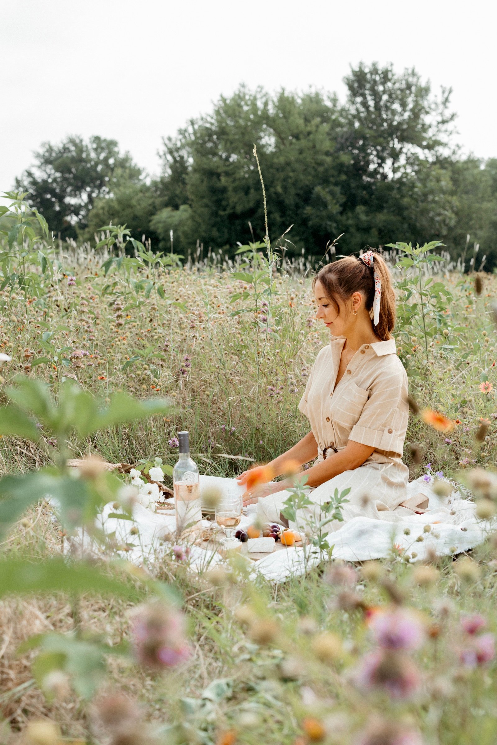 woman sitting in field of wildflowers reading