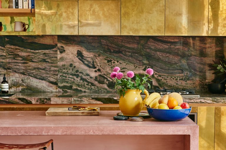 Modern kitchen with gilded cabinets and pink accents.
