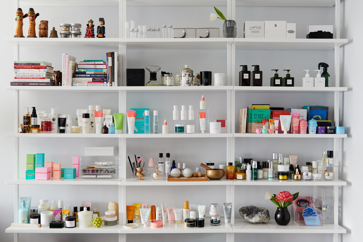 Shelves of skincare products, books, and candles - Winnie Au