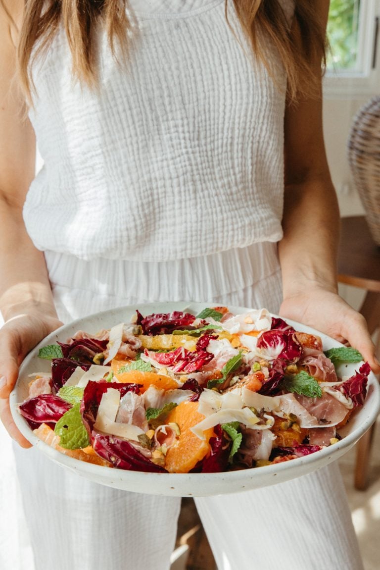 Woman carrying bowl of citrus salad.