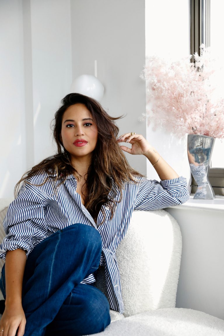 Brunette woman sitting on couch in living room.