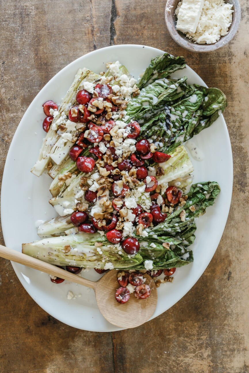 grilled romaine salad with feta and cherries on white serving platter