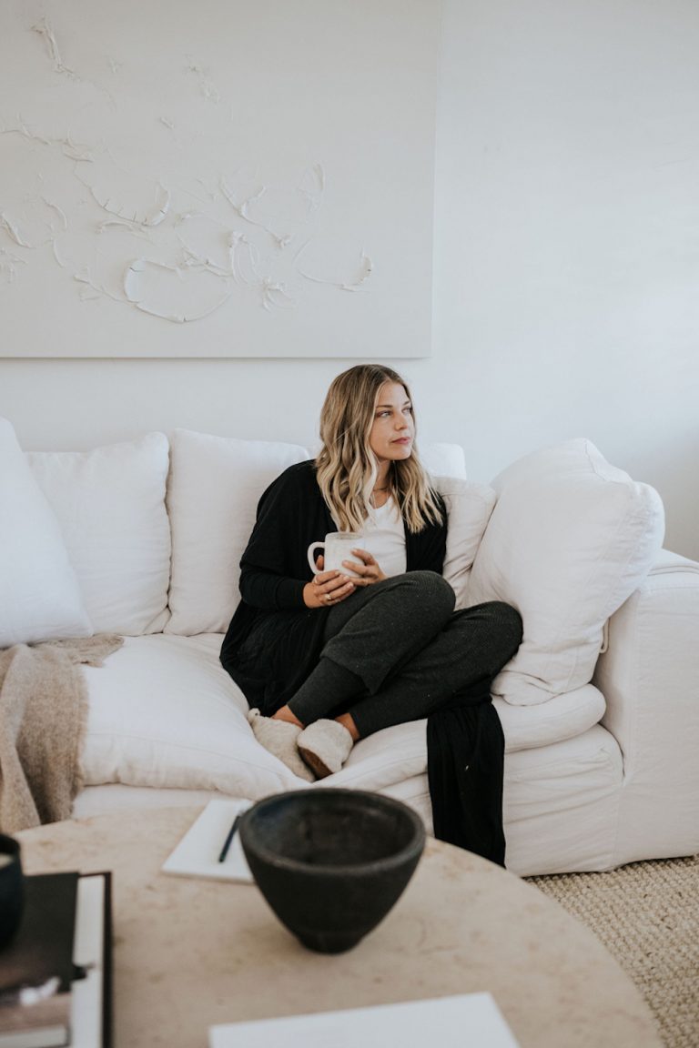 Blonde woman drinking tea on couch.