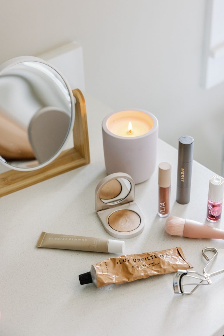 Makeup products and candle on bathroom counter.