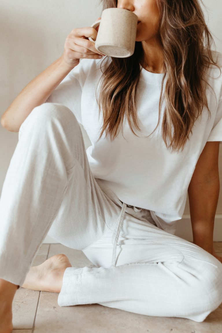 woman drinking from mug in white linen