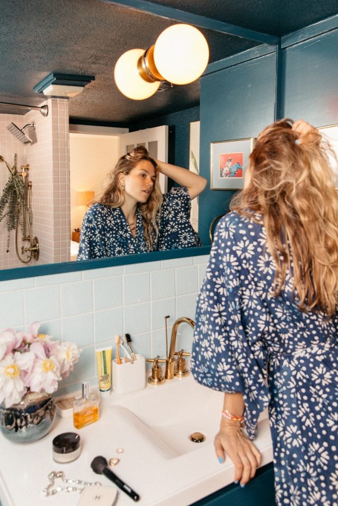 Ty Haney wearing robe looking in bathroom mirror.