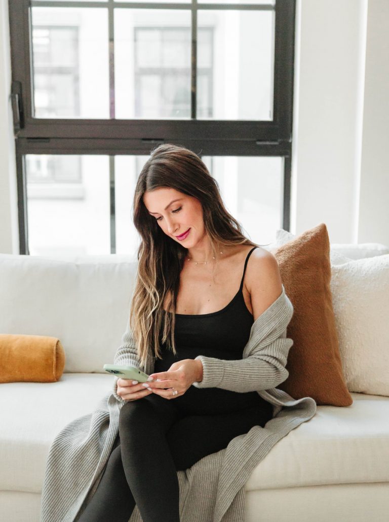 Brunette woman sitting on couch using phone.